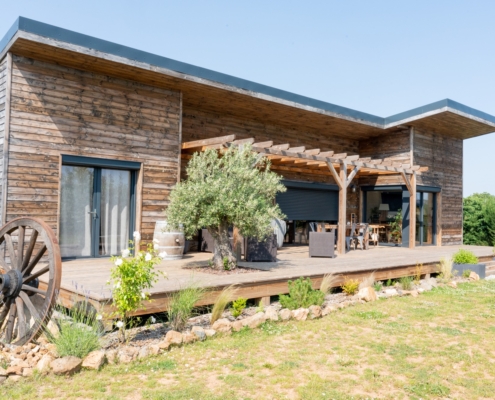 Maison à ossature bois de plain-pied avec une terrasse à l’arrière.