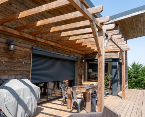 Maison à ossature bois de plain-pied avec une terrasse à l’arrière.