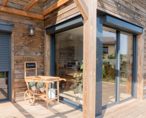 Maison à ossature bois de plain-pied avec une terrasse à l’arrière.