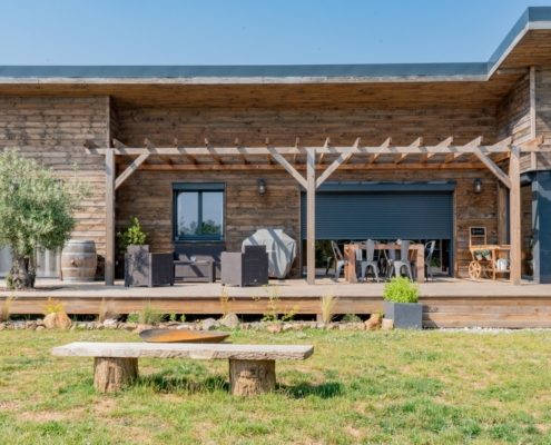 Maison à ossature bois de plain-pied avec une terrasse à l’arrière.