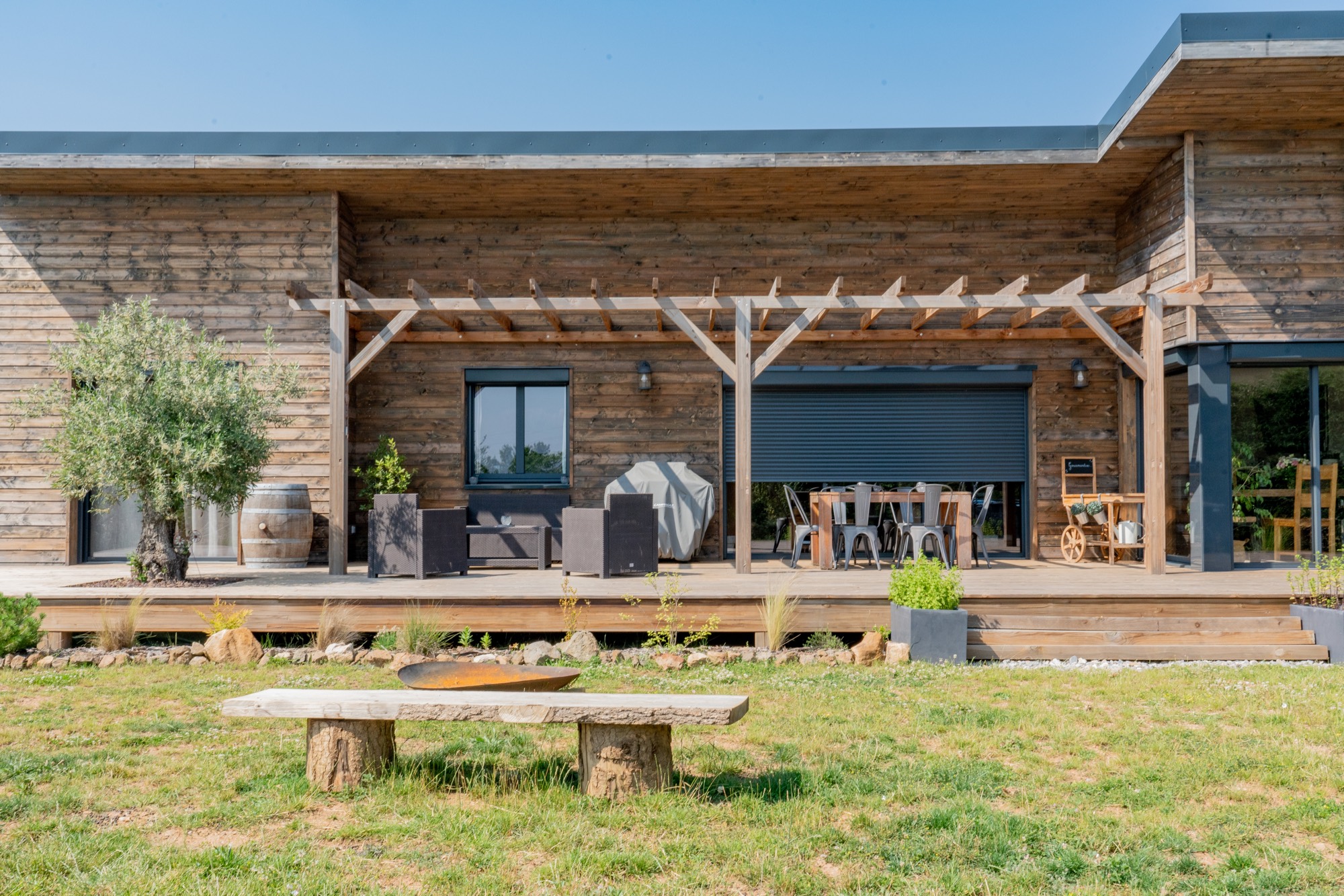 Maison à ossature bois de plain-pied avec une terrasse à l’arrière.