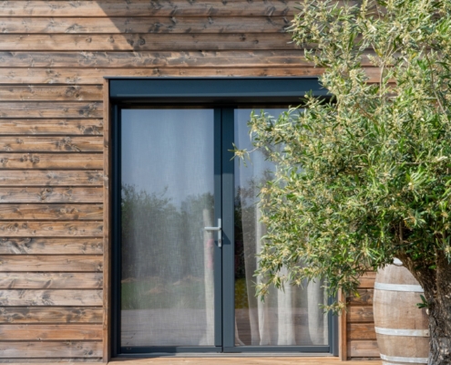 Maison à ossature bois de plain-pied avec une terrasse à l’arrière.