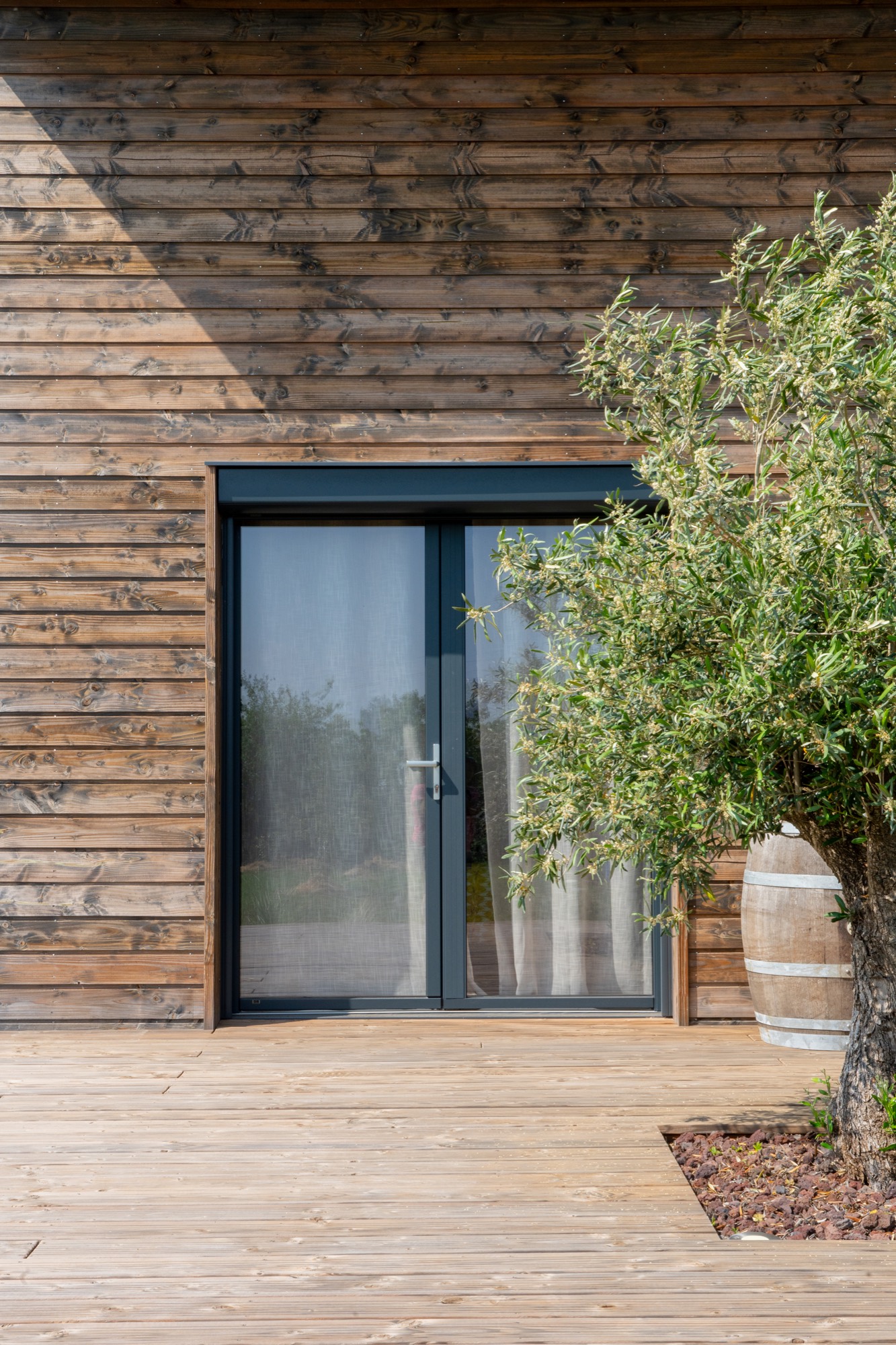 Maison à ossature bois de plain-pied avec une terrasse à l’arrière.