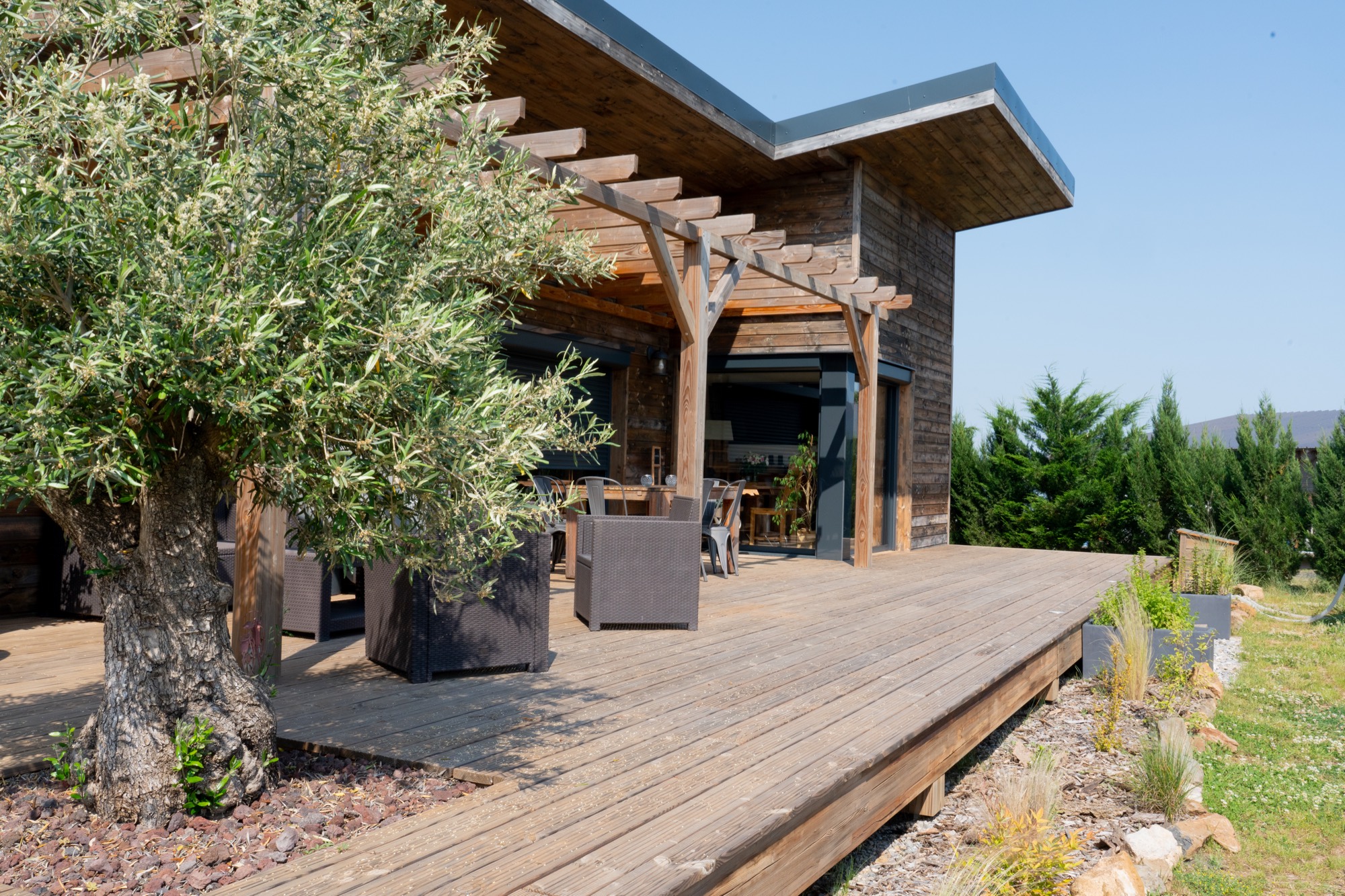 Maison à ossature bois de plain-pied avec une terrasse à l’arrière.