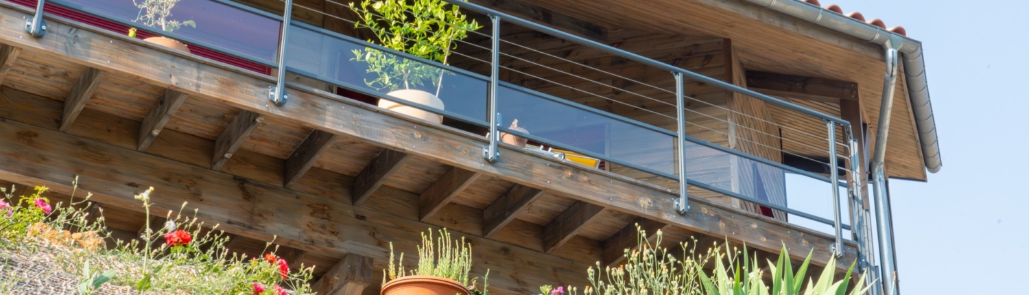 Maison à ossature bois avec une grande terrasse offrant une vue sur les montagnes