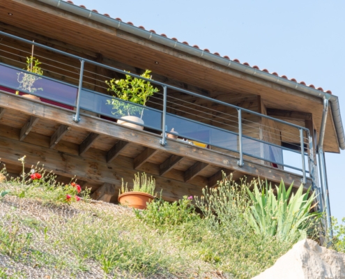 Maison à ossature bois avec une grande terrasse offrant une vue sur les montagnes