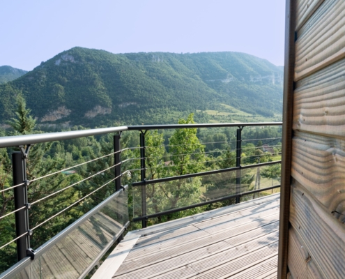 Maison à ossature bois avec une grande terrasse offrant une vue sur les montagnes
