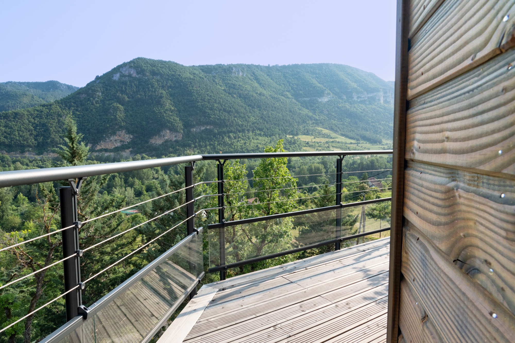 Maison à ossature bois avec une grande terrasse offrant une vue sur les montagnes