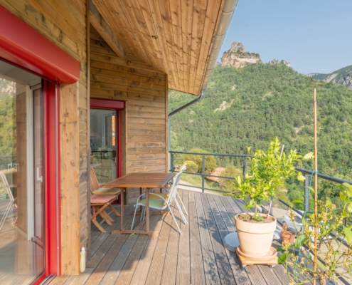 Maison à ossature bois avec une grande terrasse offrant une vue sur les montagnes