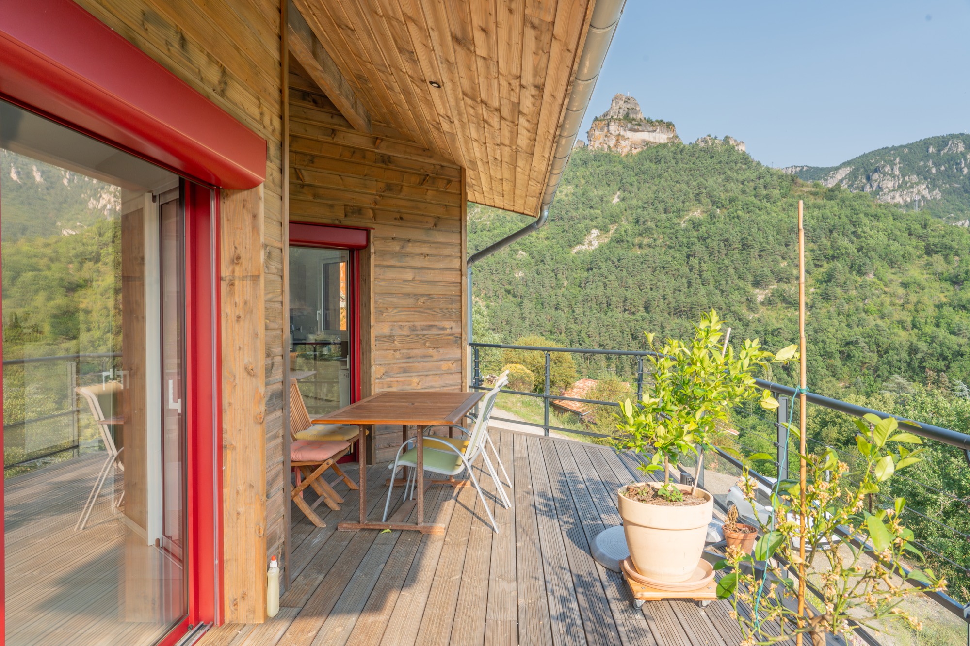 Maison à ossature bois avec une grande terrasse offrant une vue sur les montagnes